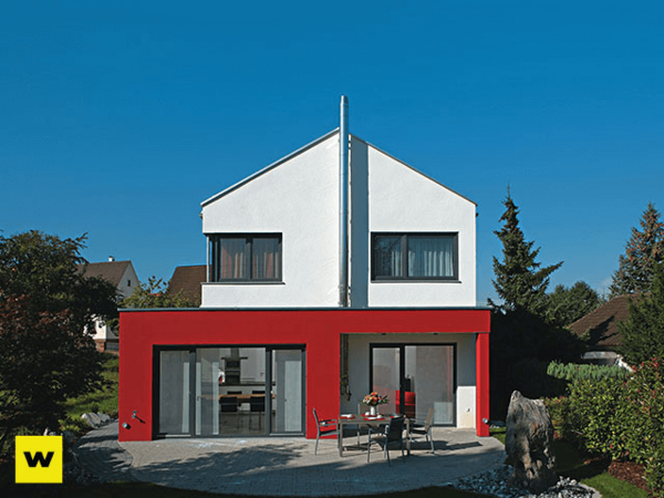 Modernes Einfamilienhaus mit roter Fassade, Flachdach und Garten unter blauem Himmel.